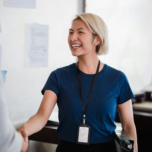 Friendly businesswoman in a blue shirt shaking hands during meeting, radiating professionalism and approachability.